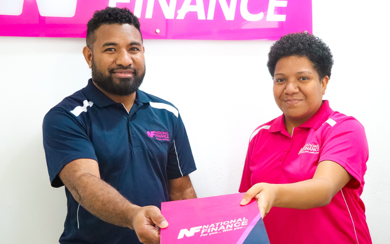 Blog Banner_Is a Loan Repayment Rebate Right for You? Pros and Cons for PNG Families_NF employees holding a National Finance brochure